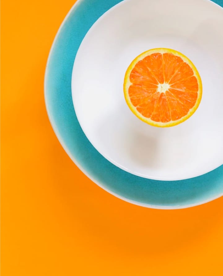 Half Orange in top right, on two bowls, with orange background