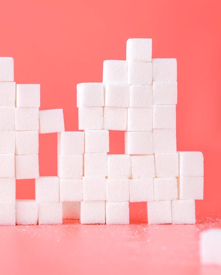 Sugar Cubes stacked into a wall with a pink background